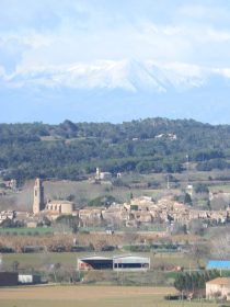 view to Corsa with snowy Pyrenees behind from rise above La Bisbal sports club on the walk